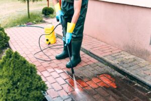 Man cleaning red concrete pavement blocks using high pressure water cleaner - pressure washing metairie